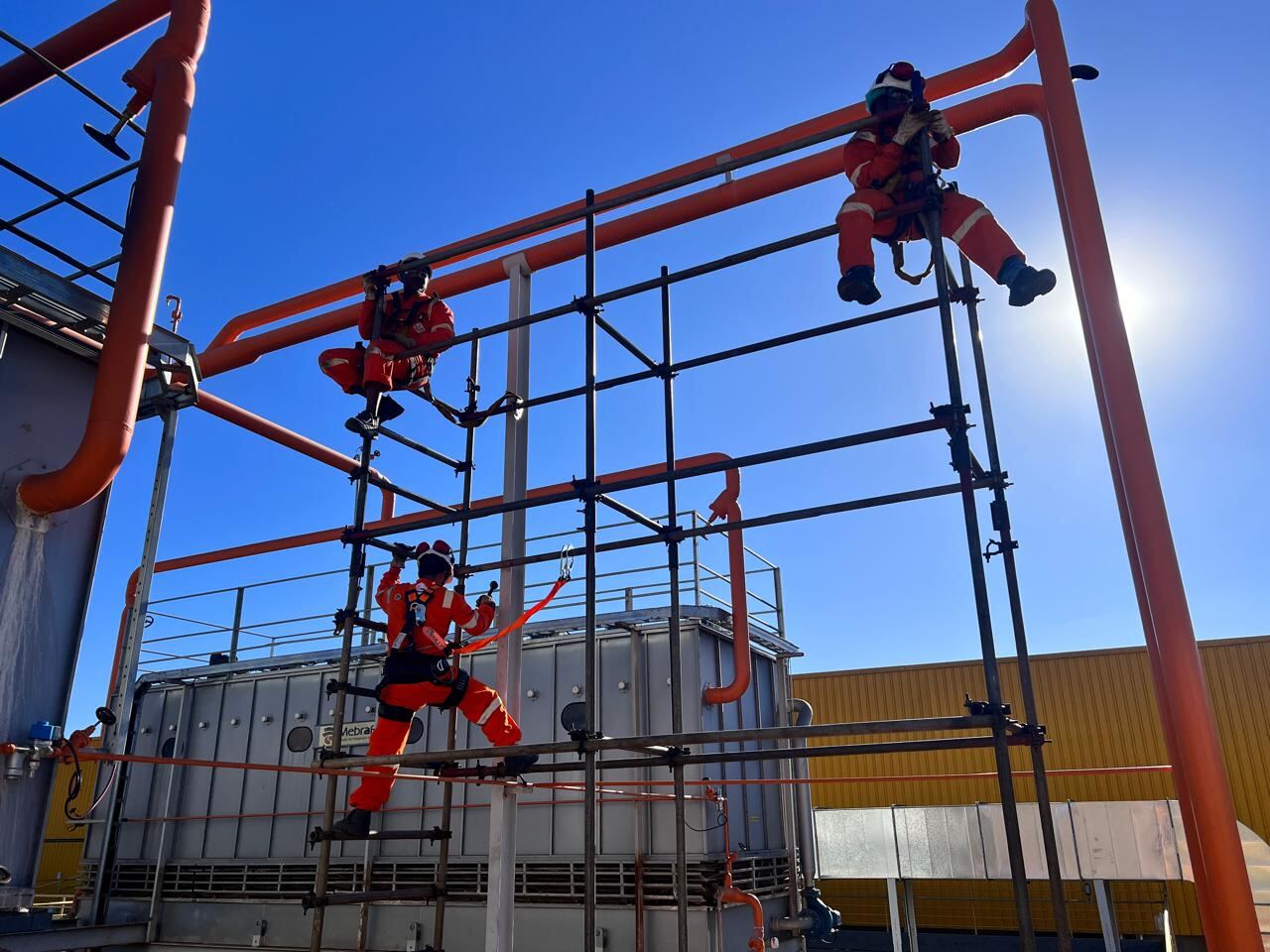 Equipe IRATA da Comando Equipamentos em estrutura tubular laranja em planta industrial — Pouso Alegre/MG