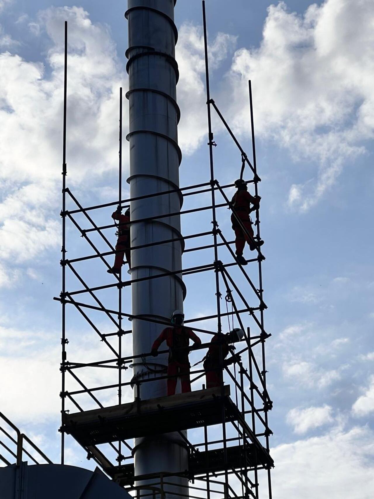 Silhueta da equipe IRATA da Comando em contraluz, trabalhando em chaminé industrial
